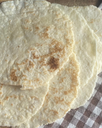 gluten free flour tortillas on a cutting board with a checkered towel