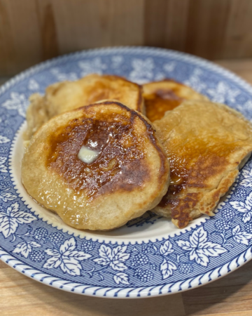 pancakes on a blue patterned plate with butter and syrup