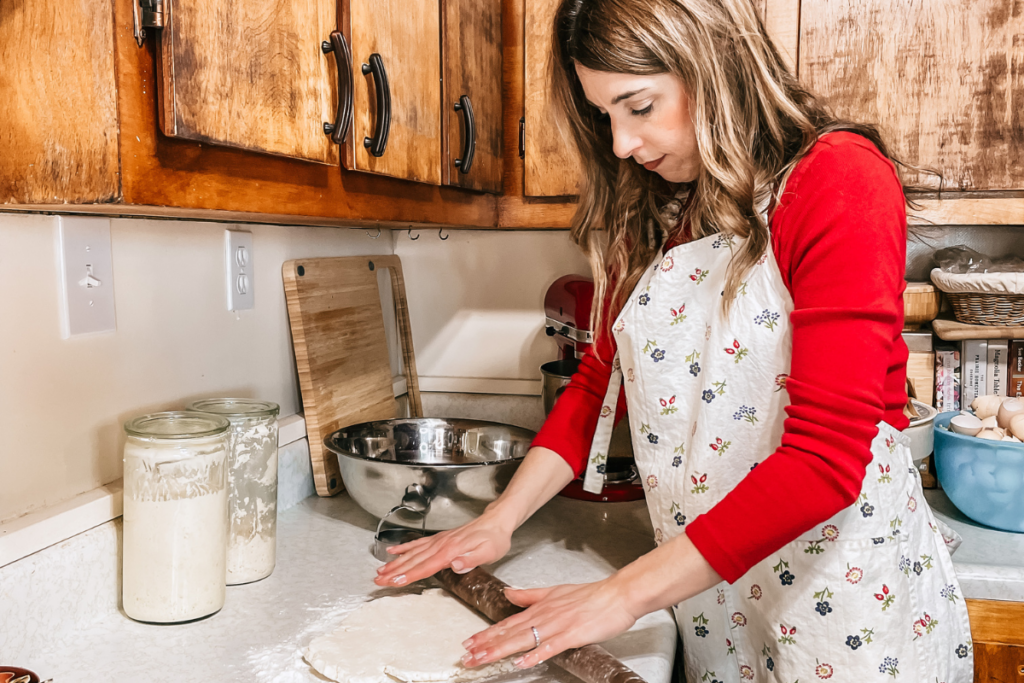 women in a red shirt rolling out dough with a rolling pin